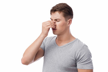 Upset sad millennial european man suffering from runny nose or headache, touching face, isolated on white background. Sinusitis, health problems, symptoms of flu and cold, covid-19, painful expression