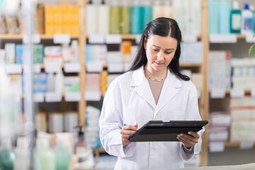Woman pharmacist makes restock, uses electronic carrier tablet of information. Checking...