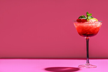 Glass of tasty Mai Tai cocktail garnished with cherries and lime on pink background