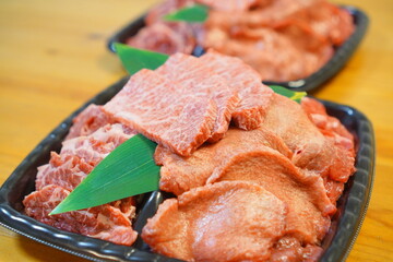 Close-up of marbled beef slices and assorted cuts arranged on a black tray for Japanese yakiniku barbecue, fresh raw meat photo