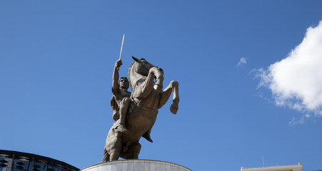 low-angle shot of the bronze statue of a warrior on a horse, with his sword raised against a clear...