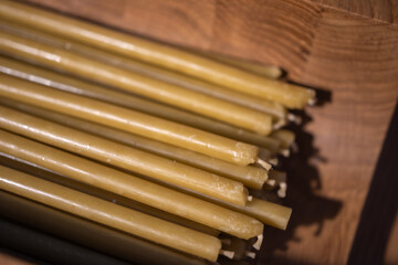 thin, yellow beeswax candles neatly arranged in a wooden bowl. The shallow depth of field creates a soft, blurred background,