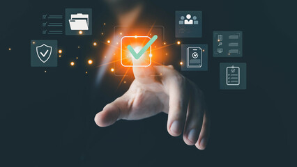 A person's hand touches a glowing green checkmark on a digital interface with business icons, symbolizing approval, completion, and quality assurance in a modern technological environment.