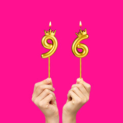Birthday on a fuchsia background with the number 96 - Hands holding number-shaped candles