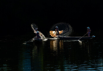 Obraz premium Throwing a fishing net on Nhu Y river, Hue, Vietnam. This is a river flowing through Hue city, where many Hue fishermen live. Photo taken in Hue, Vietnam in September 2022.