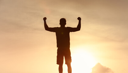 silhouetted man stands with arms raised, showcasing triumph and freedom