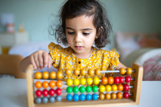 Little girl playing with colorful abacus in psychologist's office. Concept of child development and helping children with mental disorder