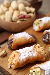 Delicious cannoli with ricotta cheese, peanuts, pistachios, chocolate and powdered sugar on table, closeup