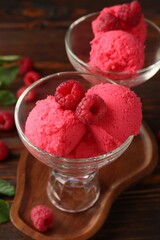 Delicious raspberry sorbet and fresh berries in dessert bowls on wooden table, closeup