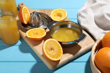 Freshly squeezed orange juice, fruits, juicer and towel on blue wooden table, closeup