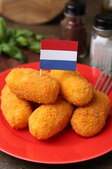 Delicious fried croquettes and flag of Netherlands on table, closeup