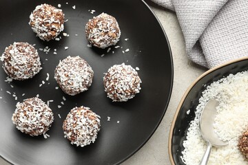 Tasty chocolate candies with coconut flakes on light table, flat lay
