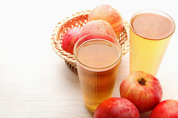 Delicious cider in glasses and red apples on white wooden table, closeup