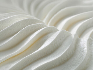 Close-up view of whipped cream swirls.  Soft,  smooth,  and  white,  the  texture  is  detailed.  Curves  and  ridges  are  apparent,  creating  a  flowing  pattern