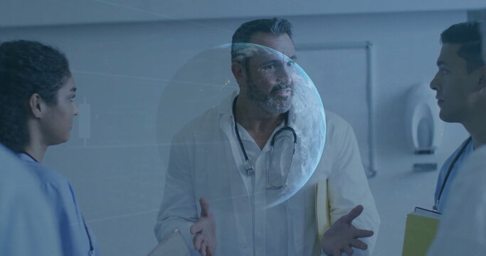 Staff wearing lab coat discussing hologram in hospital corridor, with stethoscope, yellow clipboard