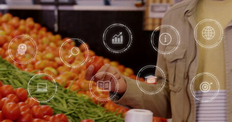Selecting mid-adult man reaching for tomato at market with green beans, digital icons, copy space