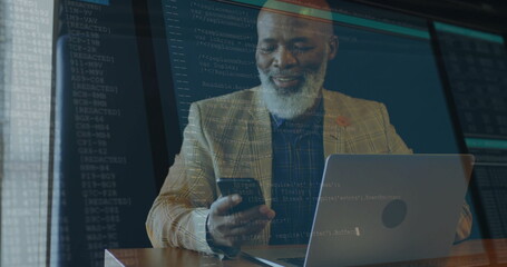 Holding smartphone, business professional analyzing code at office desk near windows, with laptop