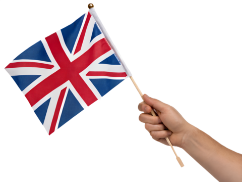 A hand holds a small UK flag on a stick against a black background
