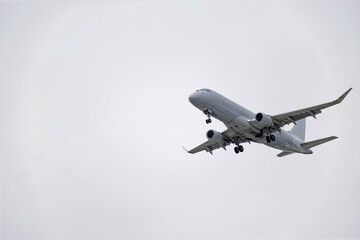 Commercial airplane flying in cloudy sky during landing approach