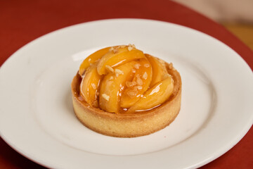 Indulge in a Delicious Peach Tart adorned with Glaze presented on an Elegant White Plate