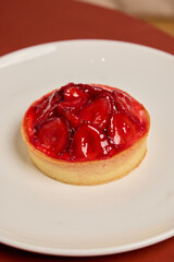 A mouthwatering and delicious Strawberry Tart beautifully presented on a pristine white plate