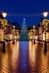 Festive Christmas tree and lights illuminate charming street at dusk for holiday joy