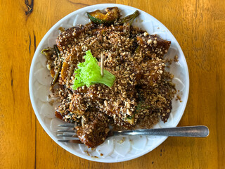 Traditional rojak salad with fruit, tofu, and dark sauce topped with crushed peanuts, served on white plate with garnish on wooden table.