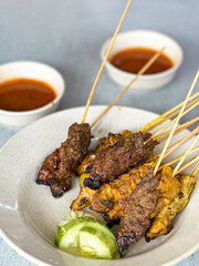 Close up view of satay (sate), a popular Malaysian street food.  Served together with peanut sauce, sliced cucumber, onion and rice cube (nasi impit)