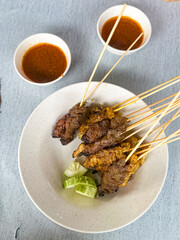 Close up view of satay (sate), a popular Malaysian street food.  Served together with peanut sauce, sliced cucumber, onion and rice cube (nasi impit)