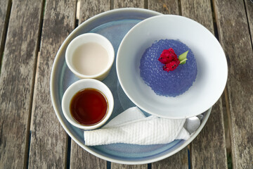 Kuih Sagu Melaka Bunga Telang, a traditional Malaysian dessert made with blue butterfly pea-infused tapioca pearls, served with palm sugar syrup and coconut milk.