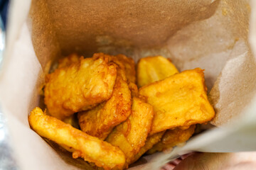 Golden brown fried bananas served in a rustic paper bag, showcasing their crispy texture and sweet aroma—perfect for street food or snack visuals.