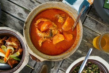 A flavorful assortment of side dishes served with rice, including spicy red snapper in tamarind gravy, crispy fried chicken, stir-fried chili eggplant, rich beef rendang, and seasoned vegetable salad.