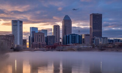 Fototapeta premium Urban Skyline at Dawn with Fog and Airplane