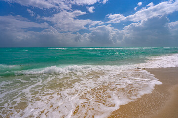 Ocean waves and sand on sky with clouds. Stormy sea waves. Summer sea beach wave. Foamy ocean waves. Summer ocean breeze. Dreamy summer beach background. Ocean splash waves.