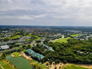 Aerial drone view of suburban homes in Kissimmee, Orlando, Florida, showing rooftops, streets, and green areas in a peaceful neighborhood setting.