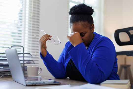 Overworked tired african female worker holding glasses feel eye strain fatigue after computer work multiracial woman suffer from pain in dry irritated eyes bad blurry vision eyesight problem
