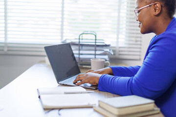 African American business woman, A female secretary work on laptop Sitting at a Desk, reports to the workplace in the office, uses a computer
