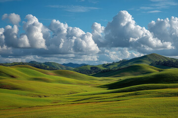 Fototapeta premium Rolling green hills under a bright blue sky with scattered clouds