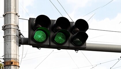 Green traffic light illuminated—modern multi-lens signal head on pole against cloudy sky and power lines, indicating vehicle movement.