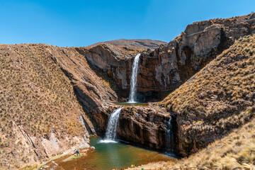 Obraz premium Majestic waterfall in Marcapomacocha, Andes of Peru, flowing over cliffs into turquoise pools, a natural attraction for adventure and eco-tourism.