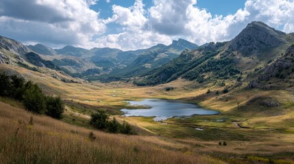 Mountainous landscape with a tranquil lake nestled in a valley under a cloudy sky