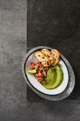 Tuna tartare with avocado mousse, bright top-lighting, overhead minimalist composition