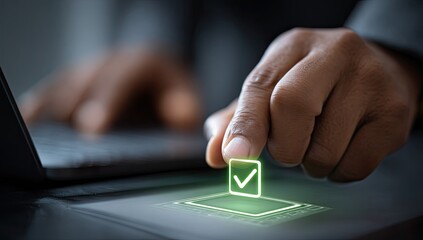 A person's hand is placing a glowing green checkmark over a digital box on a table, with a laptop in the background