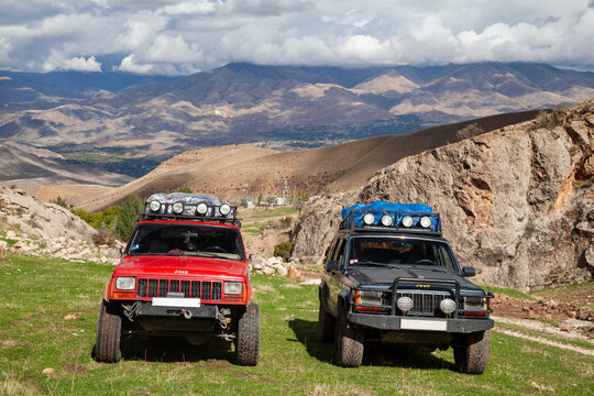 Vayots Dzor, Armenia - Mar 25, 2015 -Two old classic modified, lifted, stock 4x4 Jeep Cherokee XJs 4.0L off-road SUV vehicles with roof rack military lights, MT tires parked in mountains during a trip