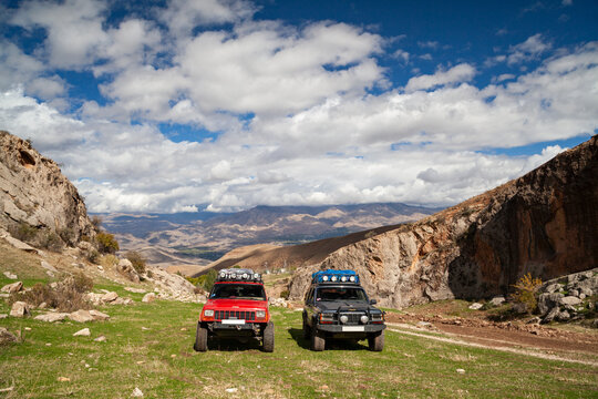 Vayots Dzor, Armenia - Mar 25, 2015 -Two old classic modified, lifted, stock 4x4 Jeep Cherokee XJs 4.0L off-road SUV vehicles with roof rack military lights, MT tires parked in mountains during a trip