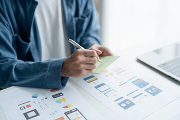 UX UI Designer Planning innovative Mobile App with Paper Wireframe Designs at Workspace.
