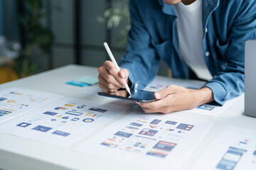 UX UI Designer Planning innovative Mobile App with Paper Wireframe Designs at Workspace.