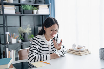 Asian Woman Engaging with Voice Assistant on Smartphone in Modern Home