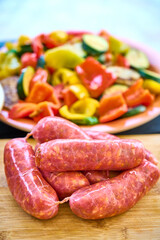 Raw Sausages on Wooden Board and Vegetable Platter