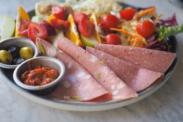 Delicious platter of fresh fruits and cold cuts on a table